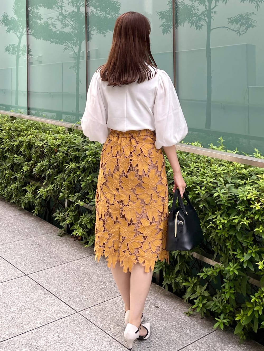 イエロー系のスカート、ホワイト系のTシャツ/カットソー、ブラック系のハンドバッグを着用したレディースの秋コーディネートの3枚目の写真