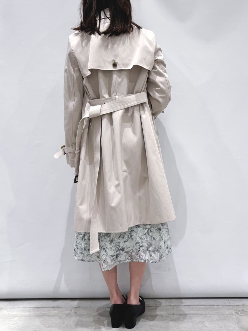 グレー系のワンピース、ベージュ系のトレンチコート、ブラック系のパンプスを着用したレディースの春コーディネートの2枚目の写真