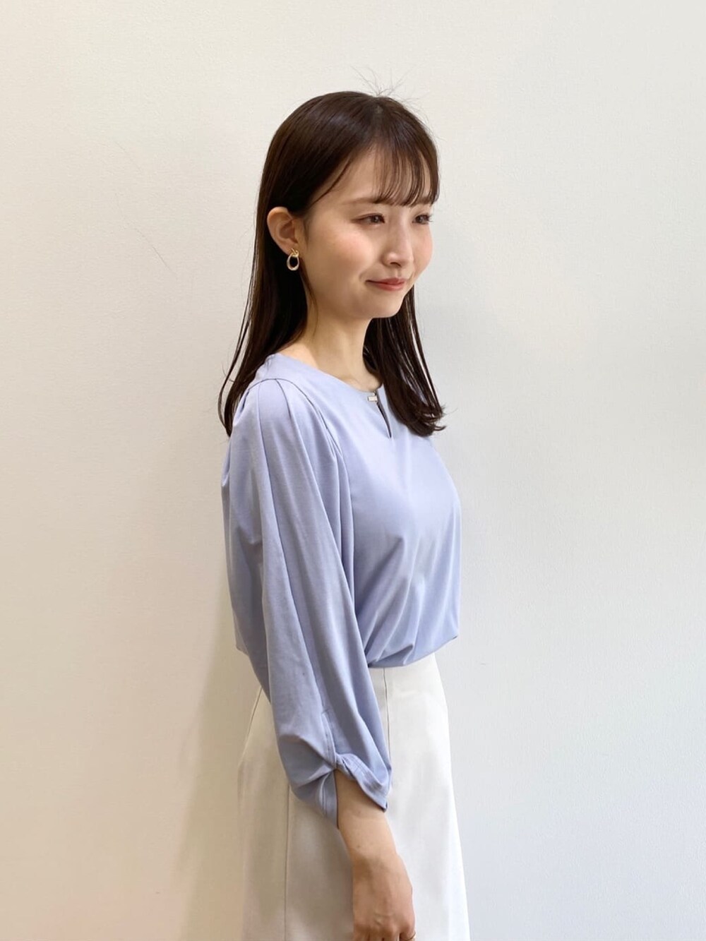 グレー系のスカート、ブルー系のTシャツ/カットソー、ホワイト系のパンプスを着用したレディースの春コーディネートの5枚目の写真