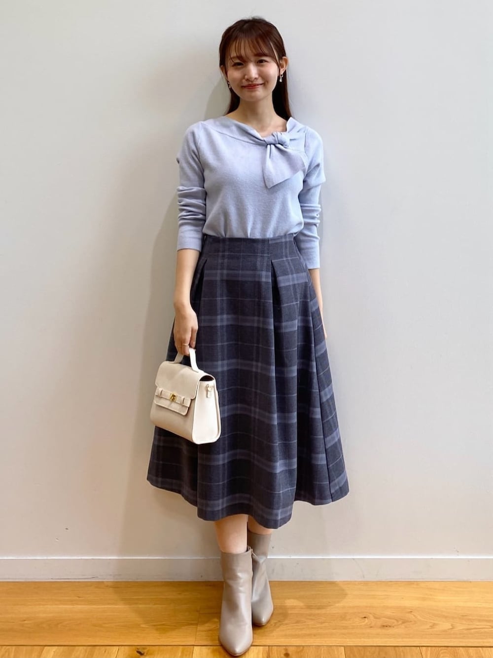 ブルー系のニット/セーター、グレー系のスカート、ホワイト系のショルダーバッグを着用したレディースの秋コーディネートの2枚目の写真