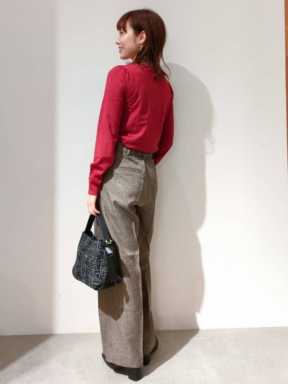 レッド系のニット/セーター、ブラウン系のその他パンツ、ブラック系のショルダーバッグを着用したレディースの秋コーディネートの7枚目の写真
