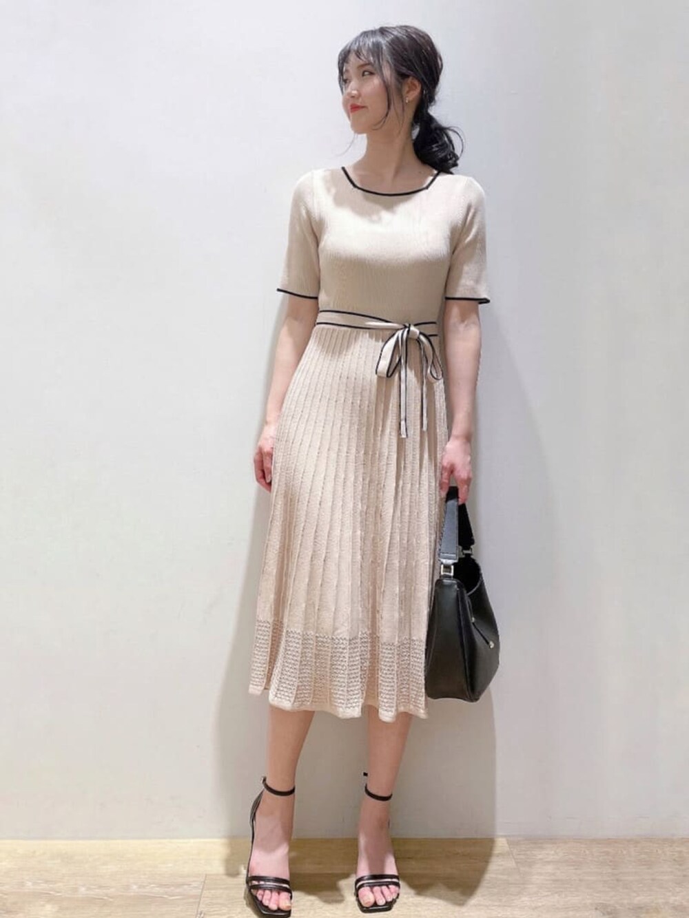 ベージュ系のワンピース、ブラック系のショルダーバッグ、ブラック系のサンダルを着用したレディースの春コーディネートの2枚目の写真