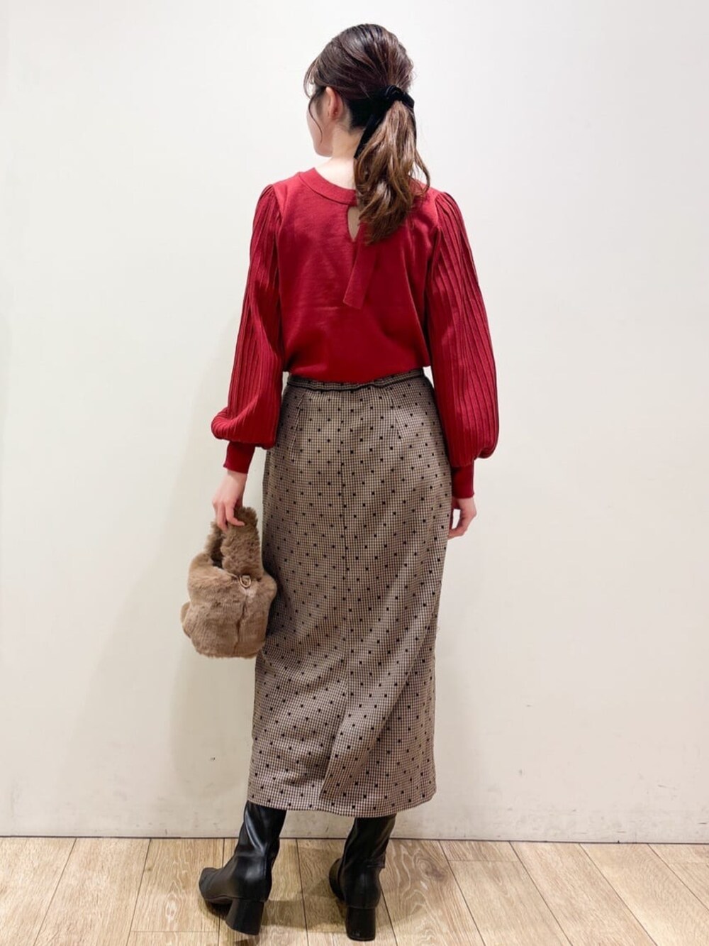 レッド系のニット/セーター、ブラウン系のスカート、ブラウン系のショルダーバッグを着用したレディースの秋コーディネートの2枚目の写真