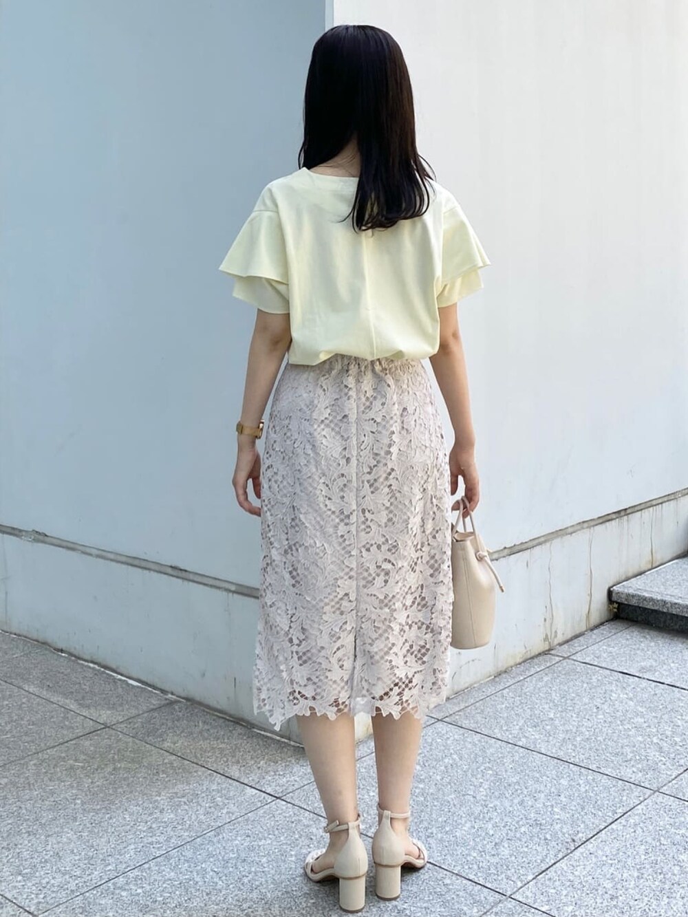 イエロー系のTシャツ/カットソー、ベージュ系のスカート、ホワイト系のショルダーバッグを着用したレディースの春コーディネートの3枚目の写真