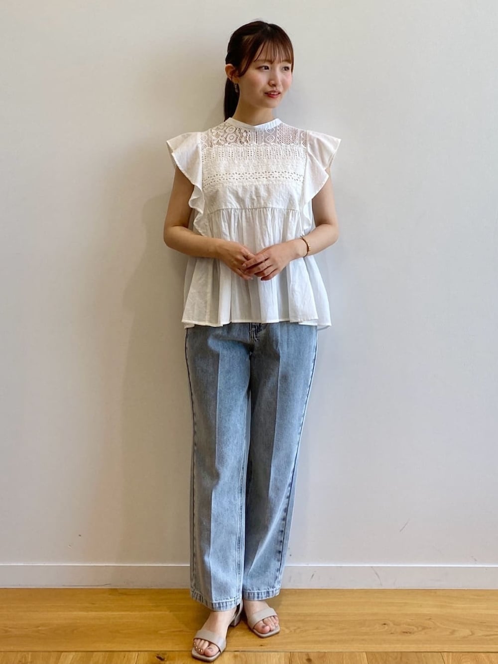 ブルー系のデニムパンツ、ベージュ系のサンダル、ホワイト系のシャツ/ブラウスを着用したレディースの夏コーディネートの2枚目の写真