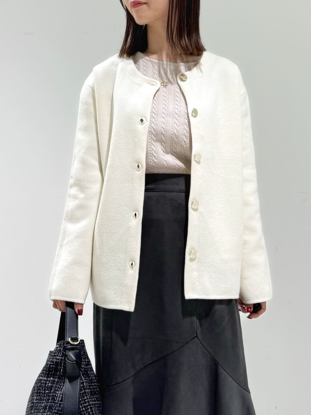 ホワイト系のカーディガン/ボレロ、ベージュ系のニット/セーター、グレー系のスカートを着用したレディースの秋コーディネートの2枚目の写真