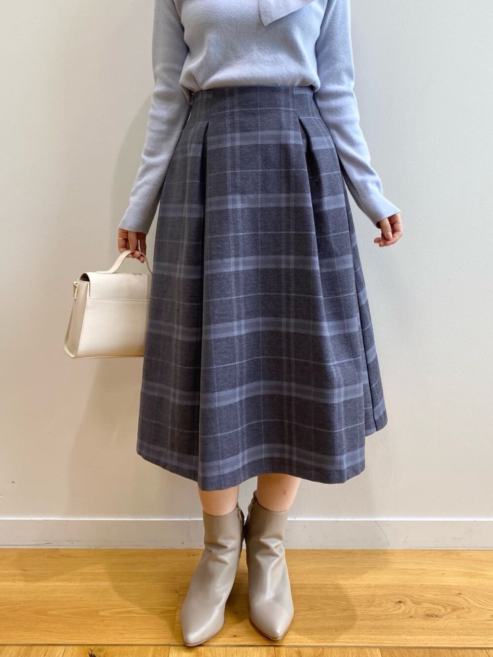 ブルー系のニット/セーター、グレー系のスカート、ホワイト系のショルダーバッグを着用したレディースの秋コーディネートの9枚目の写真