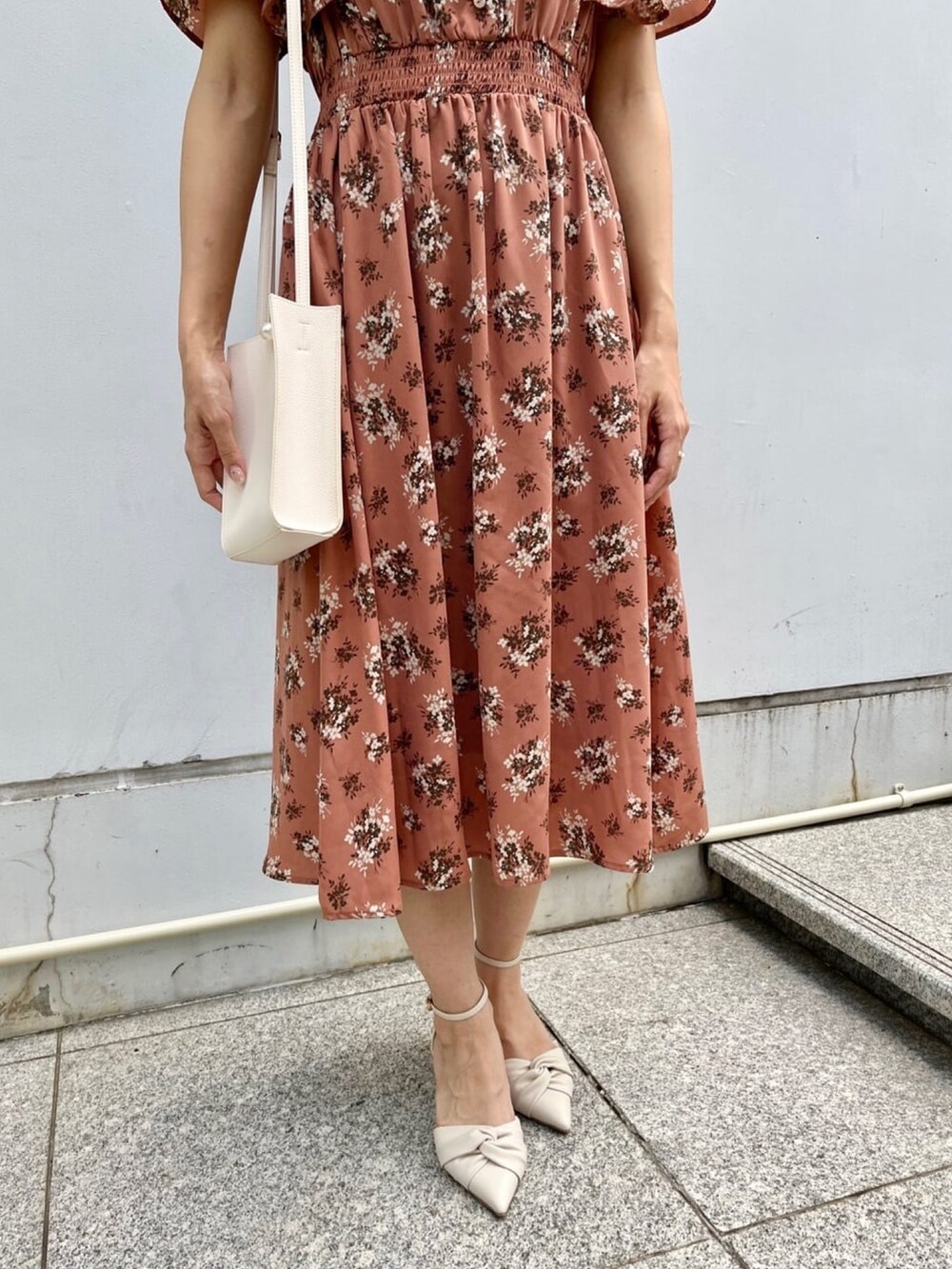 オレンジ系のワンピース、ホワイト系のショルダーバッグ、ホワイト系のパンプスを着用したレディースの夏コーディネートの5枚目の写真