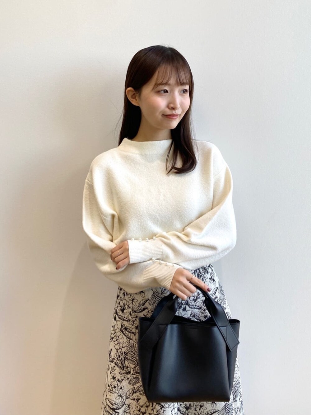 ホワイト系のニット/セーター、ブラック系のショルダーバッグ、ブラック系のブーツを着用したレディースの冬コーディネートの4枚目の写真