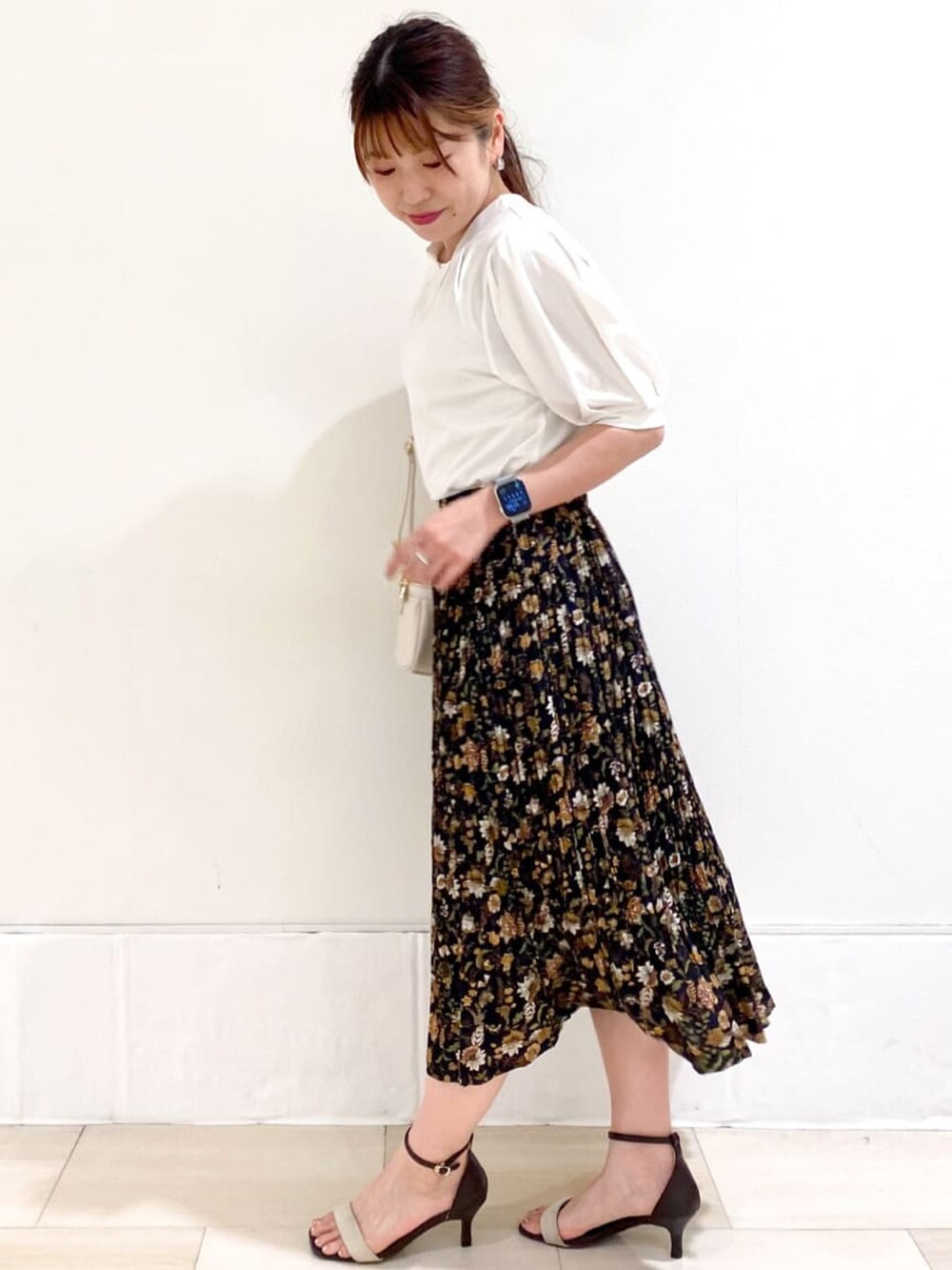 ホワイト系のショルダーバッグ、ブラック系のスカート、ベージュ系のサンダルを着用したレディースの夏コーディネートの2枚目の写真