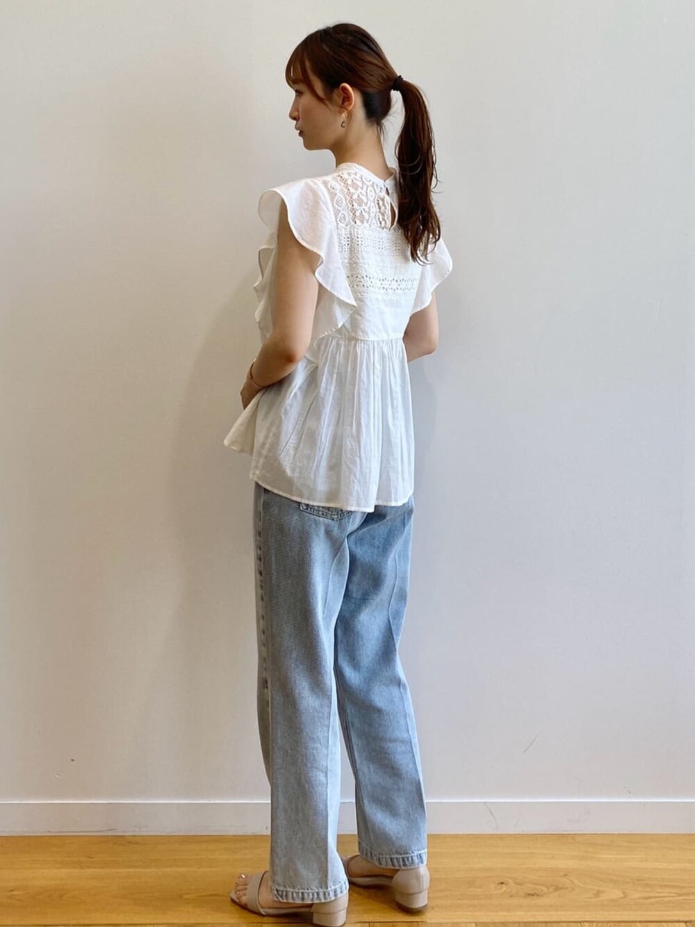 ブルー系のデニムパンツ、ベージュ系のサンダル、ホワイト系のシャツ/ブラウスを着用したレディースの夏コーディネートの5枚目の写真