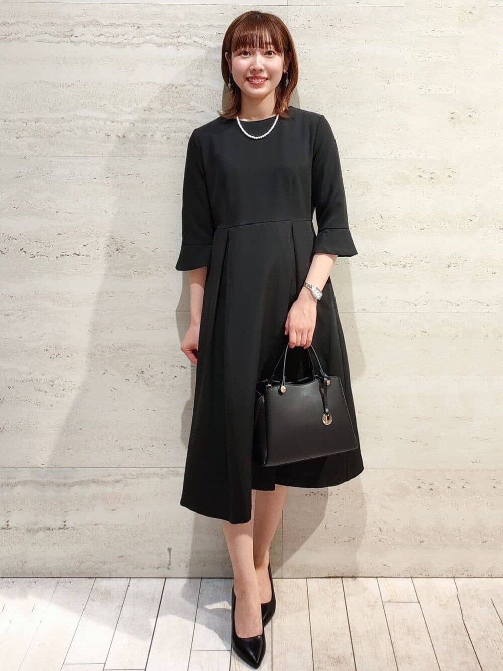 ブラック系のワンピース、ブラック系のノーカラージャケット、ブラック系のボストンバッグを着用したレディースの冬コーディネートの3枚目の写真