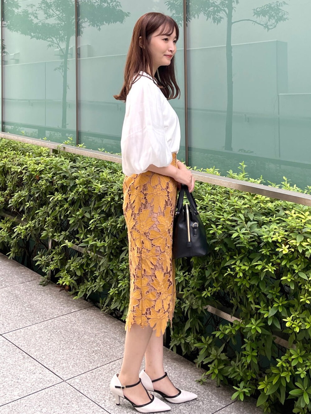 イエロー系のスカート、ホワイト系のTシャツ/カットソー、ブラック系のハンドバッグを着用したレディースの秋コーディネートの2枚目の写真