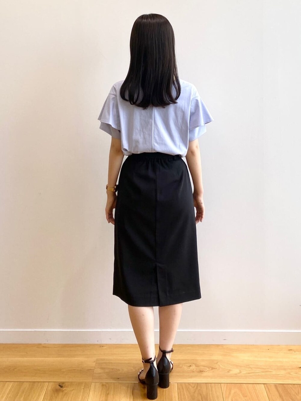 ブラック系のスカート、ブルー系のTシャツ/カットソー、ブラック系のサンダルを着用したレディースの春コーディネートの3枚目の写真