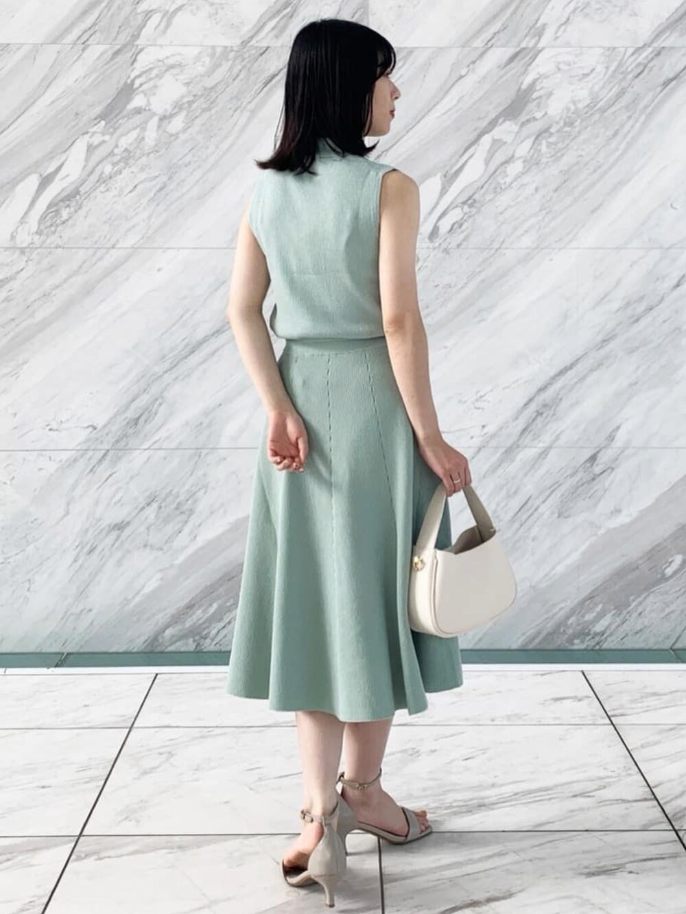 グリーン系のニット/セーター、グリーン系のスカート、グレー系のサンダルを着用したレディースの夏コーディネートの3枚目の写真