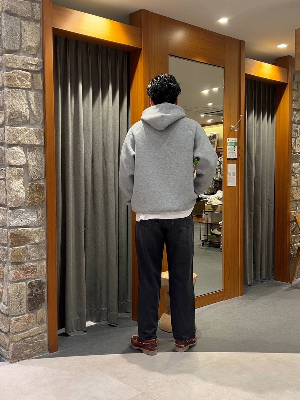 グレー系のパーカー、ブラック系のデニムパンツを着用したメンズの秋コーディネートの3枚目の写真