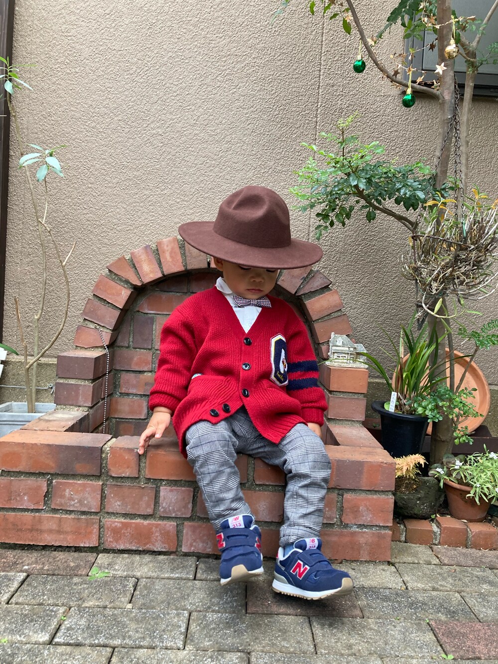 グレー系のパンツ、レッド系のカーディガン/ボレロ、ブルー系のスニーカーを着用したキッズの秋コーディネートの2枚目の写真