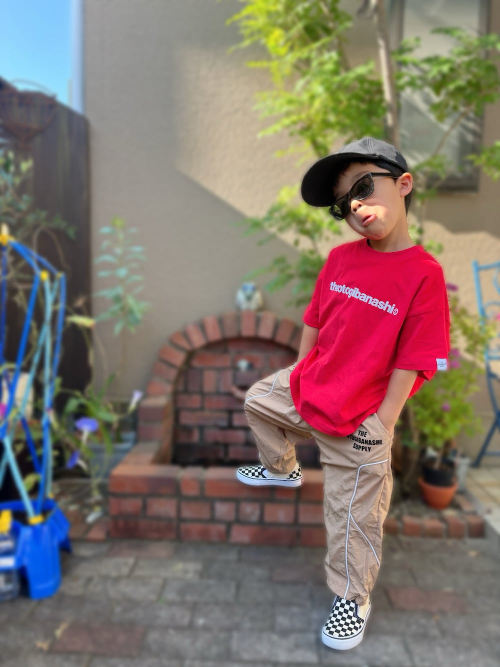 ブラック系のスリッポン、レッド系のTシャツ/カットソー、ベージュ系のパンツを着用したキッズの夏コーディネートの2枚目の写真