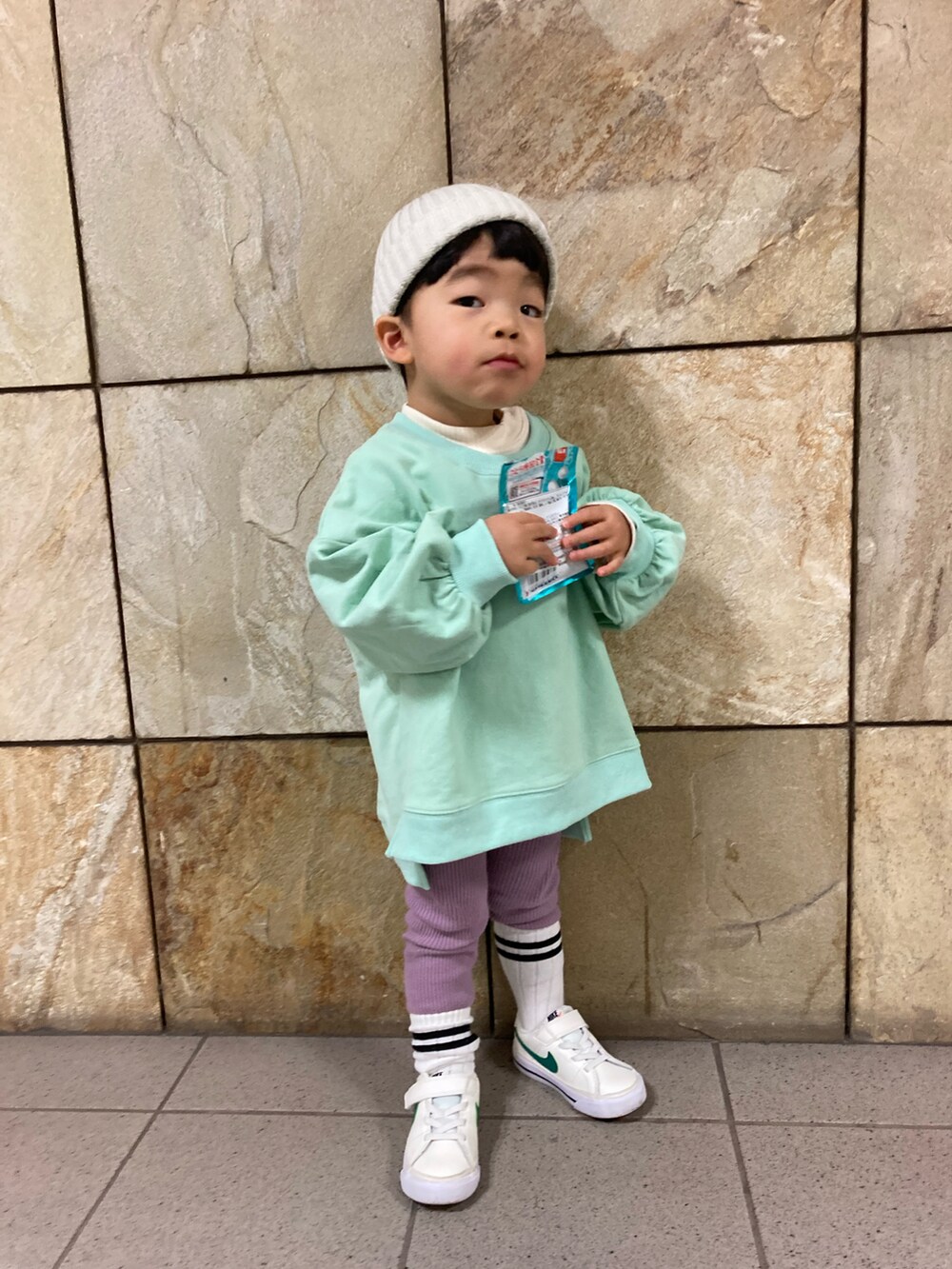 グリーン系のスウェット、ホワイト系のスニーカー、ホワイト系のニットキャップ/ビーニーを着用したキッズの冬コーディネートの2枚目の写真