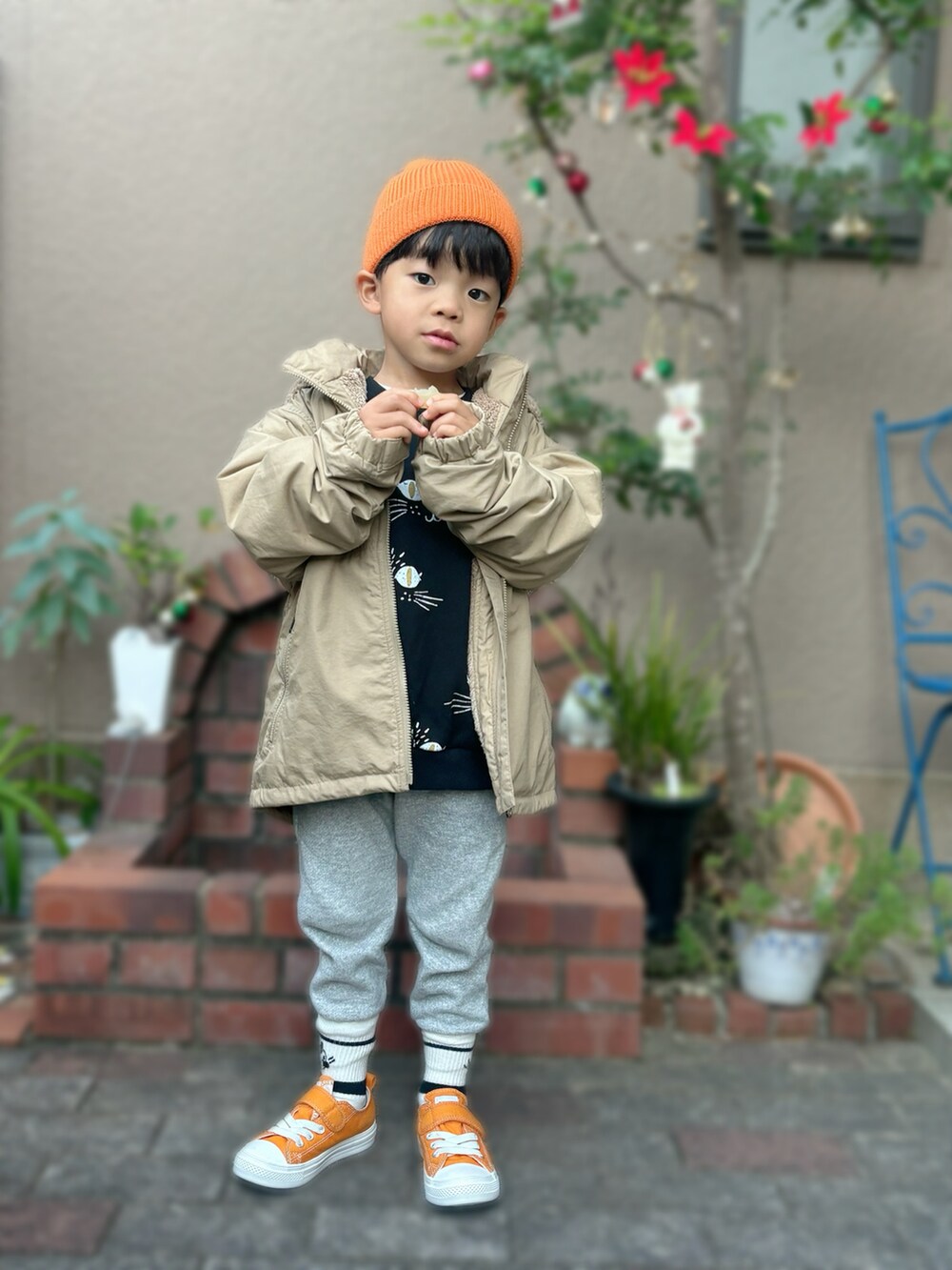 ベージュ系のナイロンジャケット、ブラック系のスウェット、オレンジ系のスニーカーを着用したキッズの秋コーディネートの3枚目の写真