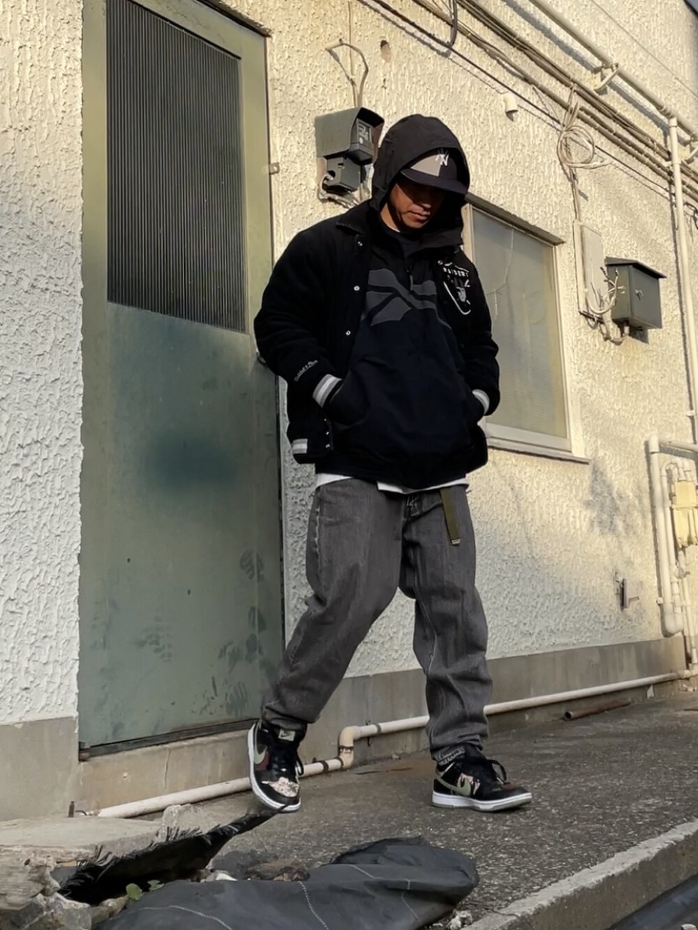 ブラック系のスニーカー、ブラック系のデニムパンツ、ブラック系のスタジャンを着用したメンズの冬コーディネートの2枚目の写真
