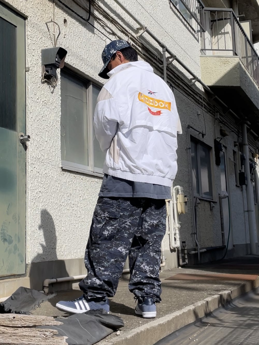 ブルー系のスニーカー、ブルー系のカーゴパンツ、ホワイト系のナイロンジャケットを着用したメンズの春コーディネートの2枚目の写真