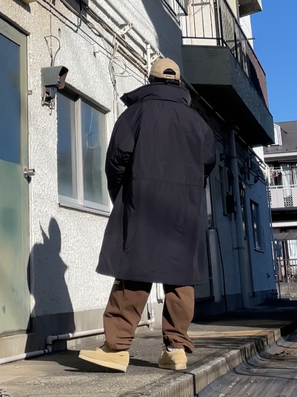 ベージュ系のモカシン/デッキシューズ、ブラウン系のスウェットパンツ、ブラック系のジャケット/アウターを着用したメンズの冬コーディネートの2枚目の写真