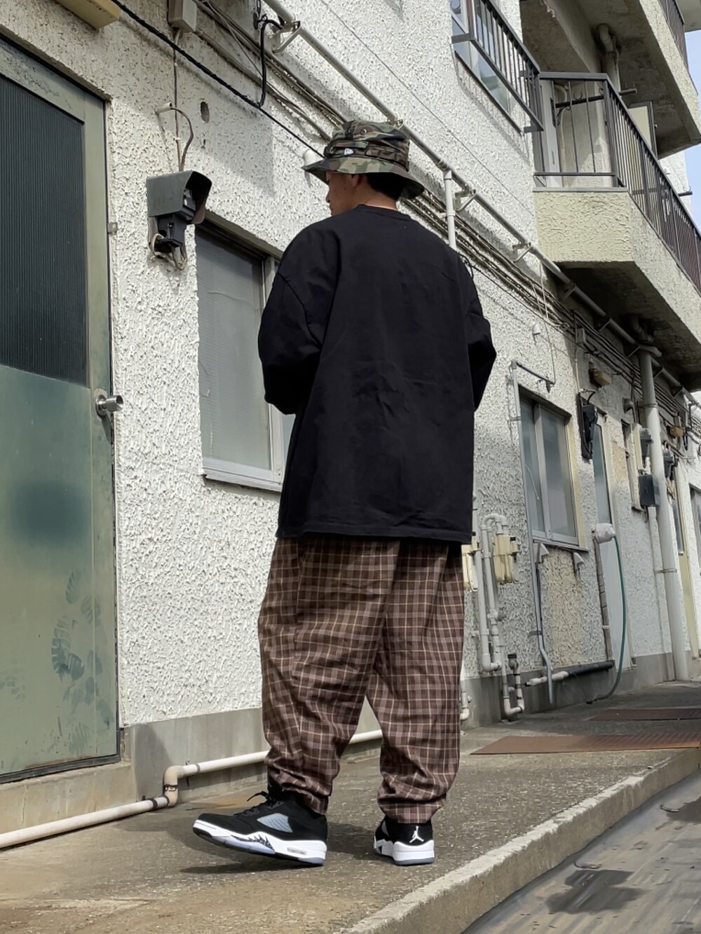 ブラック系のスニーカー、ブラウン系のその他パンツ、ブラック系のTシャツ/カットソーを着用したメンズの春コーディネートの2枚目の写真