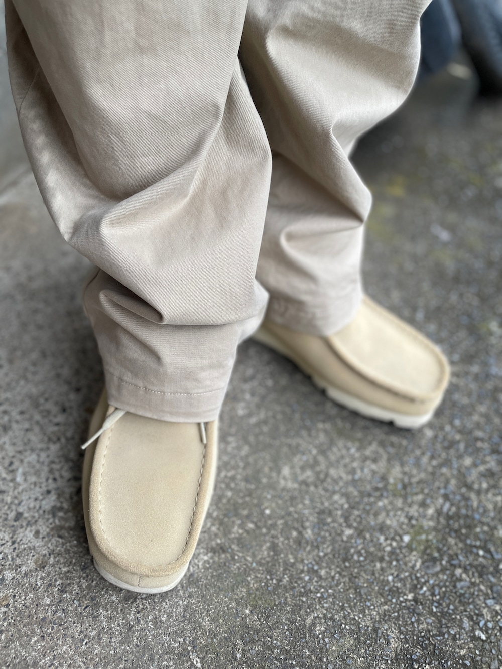 ベージュ系のチノパンツ、ブルー系のニット/セーター、ベージュ系のモカシン/デッキシューズを着用したメンズの夏コーディネートの3枚目の写真