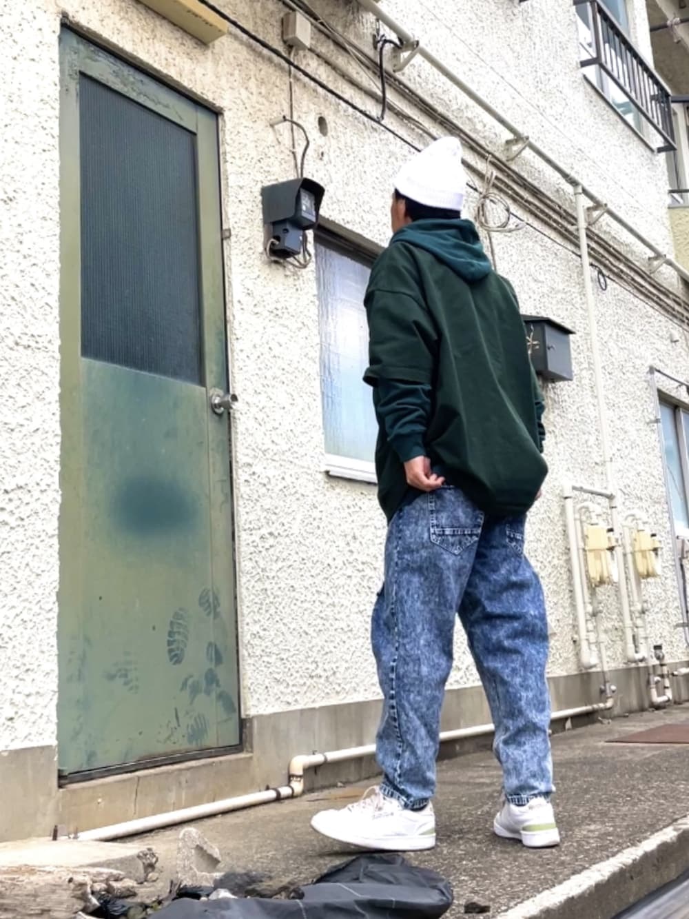 ホワイト系のスニーカー、ブルー系のデニムパンツ、グリーン系のTシャツ/カットソーを着用したメンズの冬コーディネートの3枚目の写真