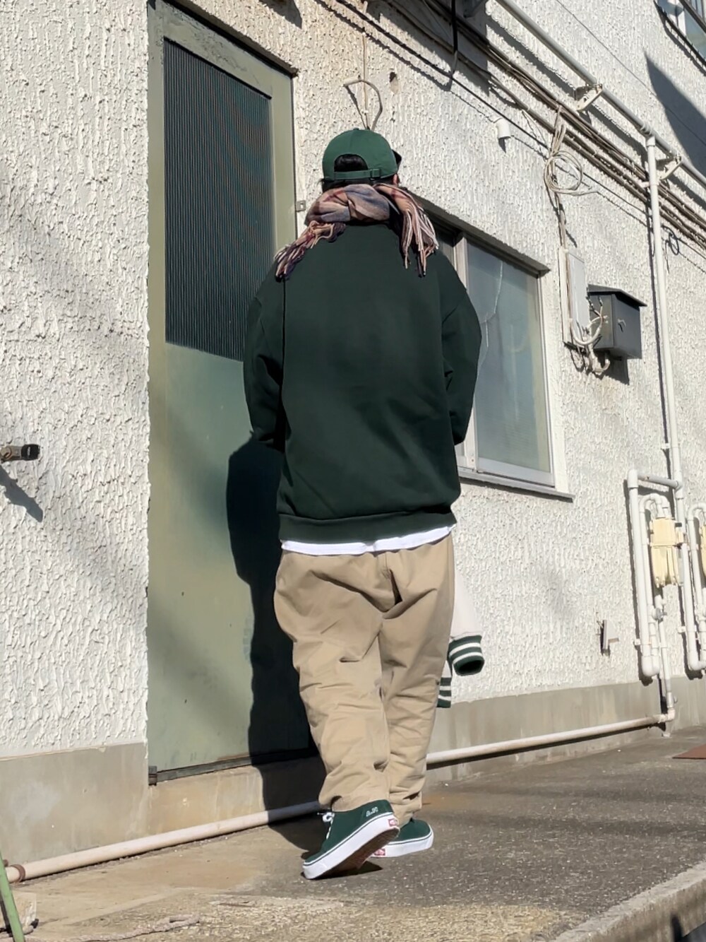グリーン系のスニーカー、ベージュ系のチノパンツ、グリーン系のスウェットを着用したメンズの冬コーディネートの2枚目の写真
