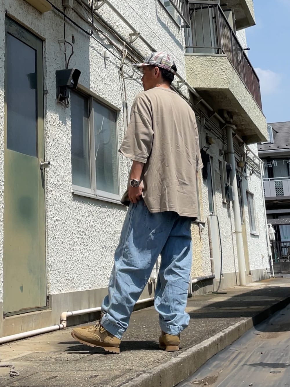 ブルー系のデニムパンツ、グリーン系のTシャツ/カットソー、ベージュ系のブーツを着用したメンズの夏コーディネートの2枚目の写真