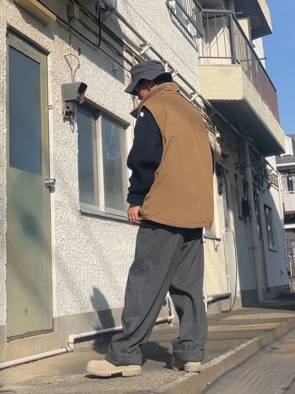 ブラウン系のベスト、ブルー系のニット/セーター、グレー系のパンツを着用したメンズの冬コーディネートの2枚目の写真