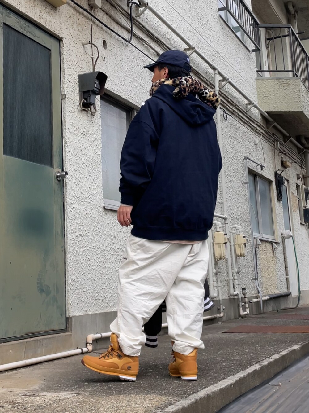 ブラウン系のブーツ、ホワイト系のチノパンツ、ブルー系のパーカーを着用したメンズの冬コーディネートの2枚目の写真