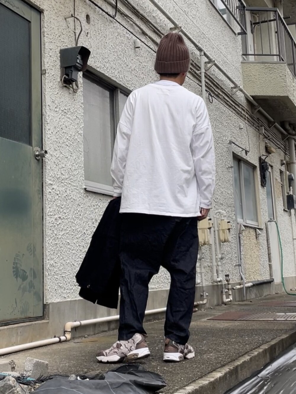 ブラウン系のスニーカー、ブラック系のデニムパンツ、ホワイト系のTシャツ/カットソーを着用したメンズの秋コーディネートの3枚目の写真