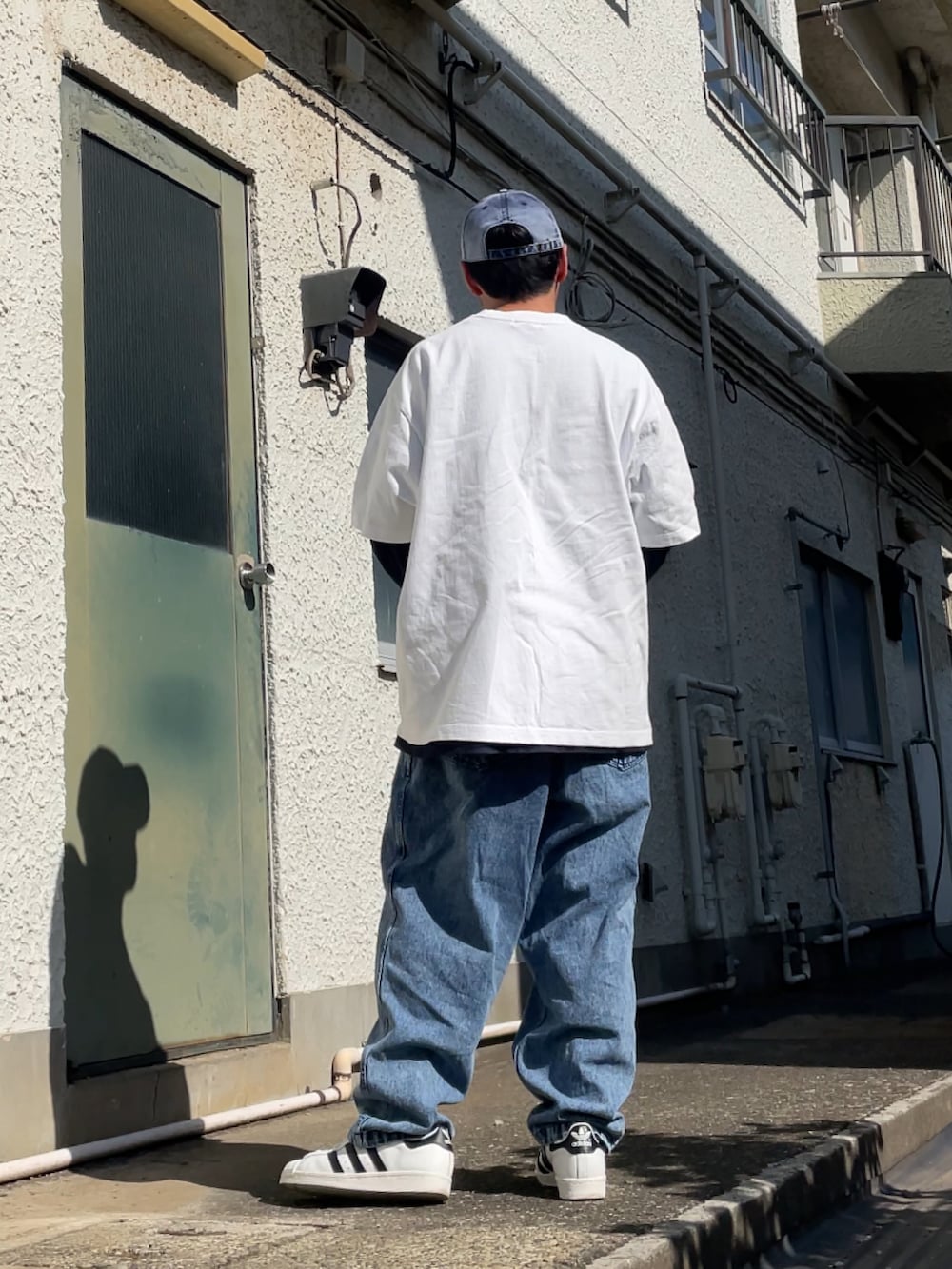 ホワイト系のスニーカー、ブルー系のデニムパンツ、ホワイト系のTシャツ/カットソーを着用したメンズの春コーディネートの2枚目の写真