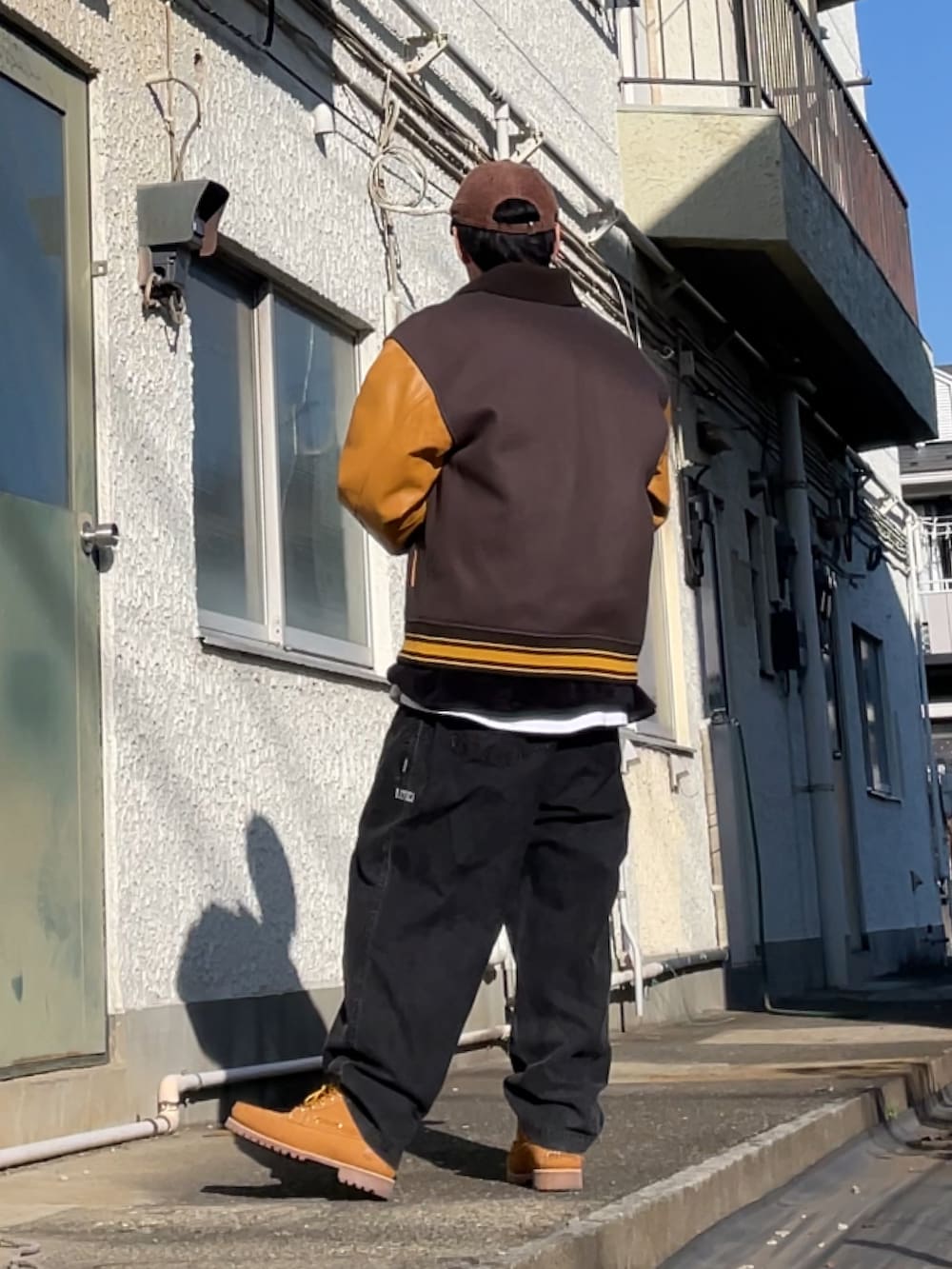 イエロー系のブーツ、グレー系のその他パンツ、ブラック系のトップスを着用したメンズの冬コーディネートの2枚目の写真