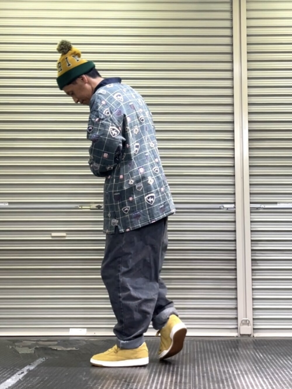 ベージュ系のスニーカー、ブラック系のデニムパンツ、グリーン系のポロシャツを着用したメンズの秋コーディネートの3枚目の写真