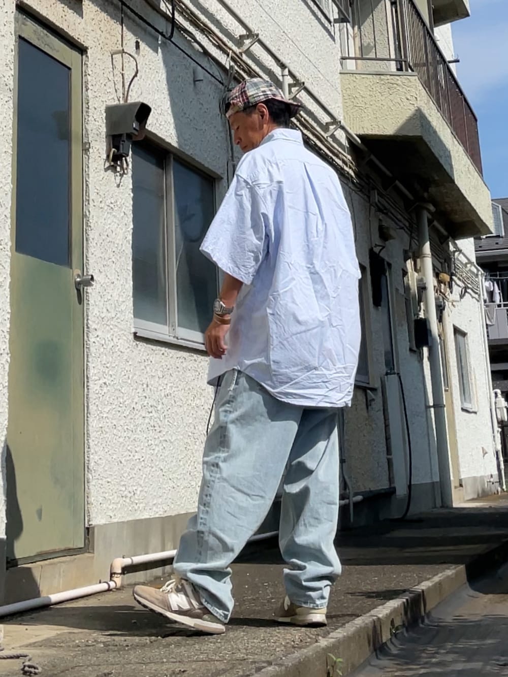 ブルー系のデニムパンツ、ブルー系のシャツ/ブラウス、ベージュ系のスニーカーを着用したメンズの夏コーディネートの2枚目の写真