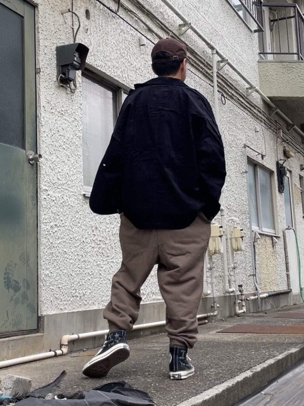 ブラック系のスニーカー、ブラウン系のパンツ、ホワイト系のTシャツ/カットソーを着用したメンズの秋コーディネートの2枚目の写真