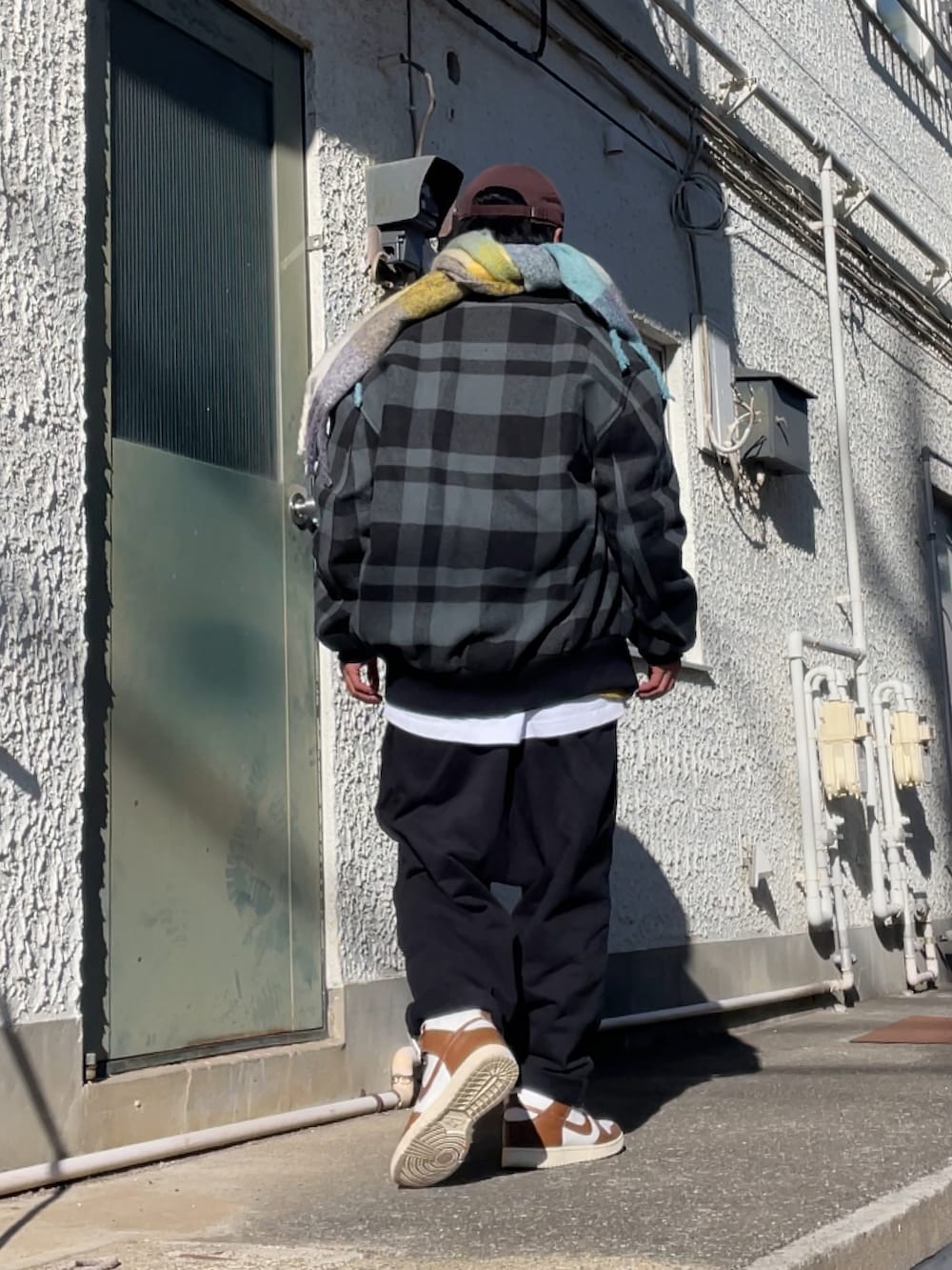 ブラウン系のスニーカー、ブラック系のその他パンツ、グレー系のスタジャンを着用したメンズの冬コーディネートの2枚目の写真