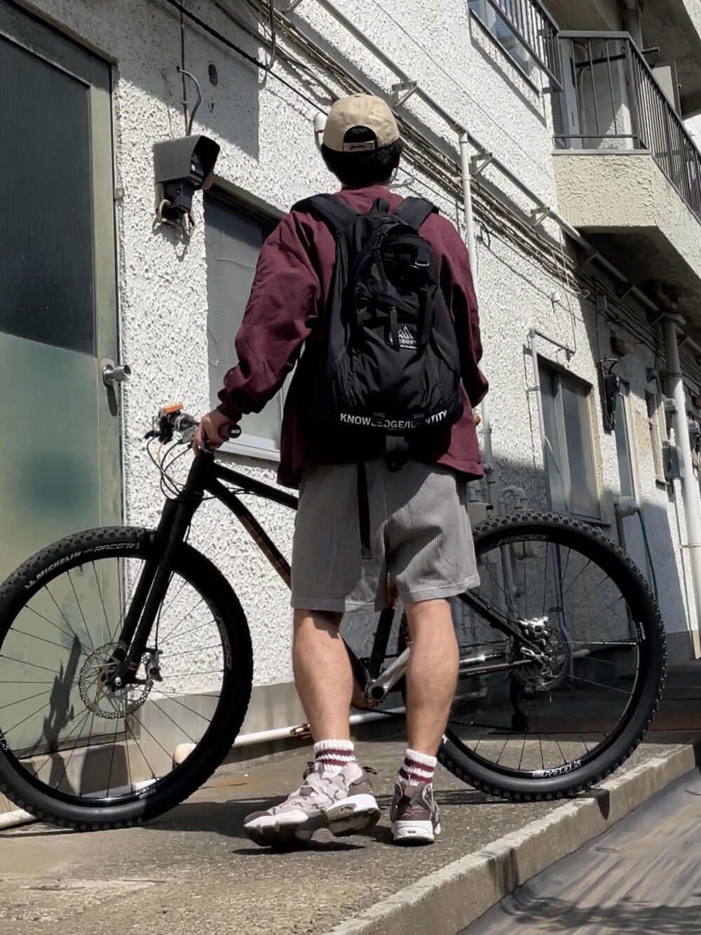 ブラウン系のスニーカー、グレー系のその他パンツ、レッド系のスウェットを着用したメンズの春コーディネートの2枚目の写真