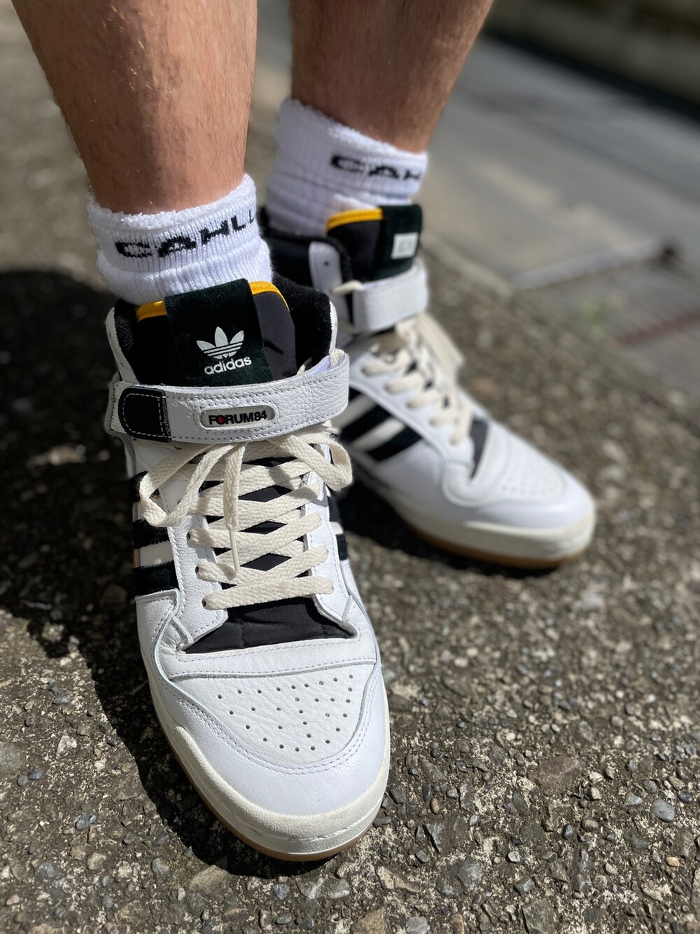 ホワイト系のスニーカー、ベージュ系のチノパンツ、ブラック系のTシャツ/カットソーを着用したメンズの夏コーディネートの3枚目の写真