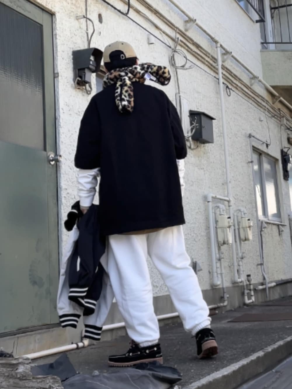 ブラック系のモカシン/デッキシューズ、ホワイト系のその他パンツ、ブラック系のTシャツ/カットソーを着用したメンズの冬コーディネートの2枚目の写真