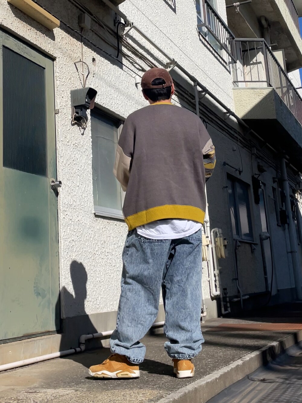 ブラウン系のスニーカー、ブルー系のデニムパンツ、イエロー系のニット/セーターを着用したメンズの春コーディネートの2枚目の写真