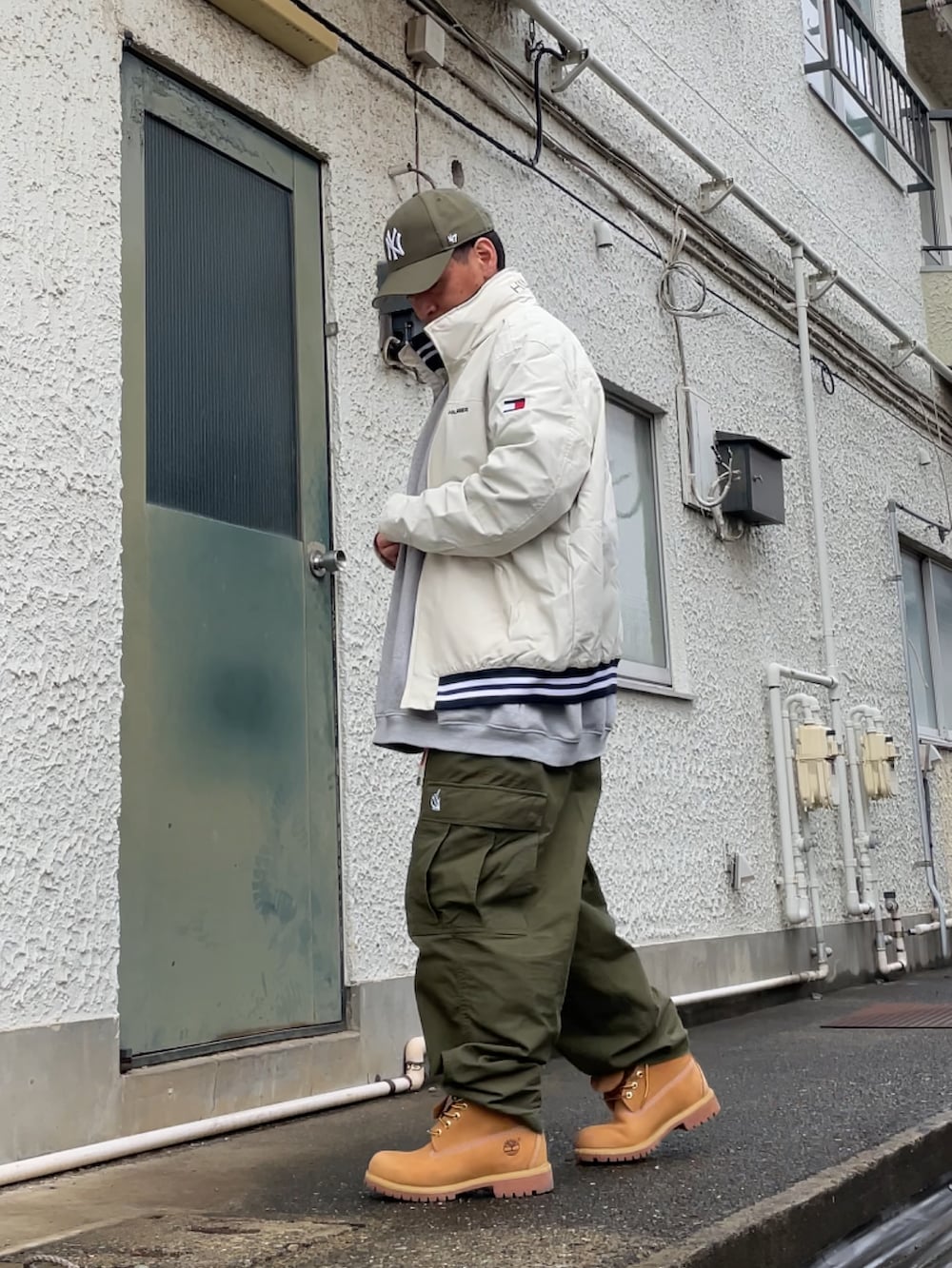 イエロー系のブーツ、グリーン系のカーゴパンツ、グレー系のスウェットを着用したメンズの春コーディネートの2枚目の写真