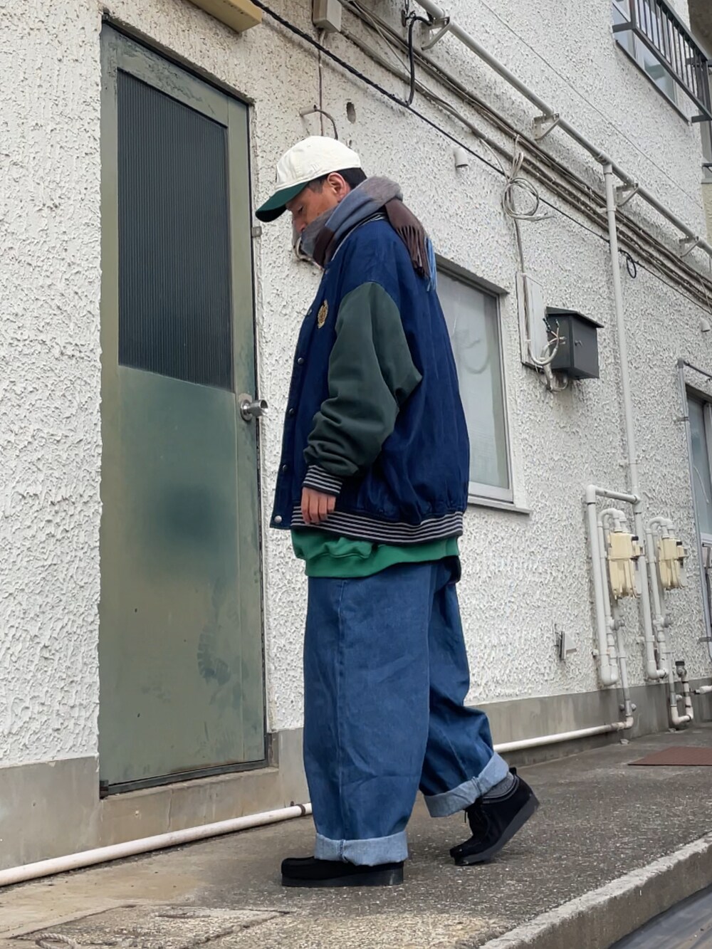 ブラック系のモカシン/デッキシューズ、ブルー系のデニムパンツ、グリーン系のスウェットを着用したメンズの春コーディネートの2枚目の写真