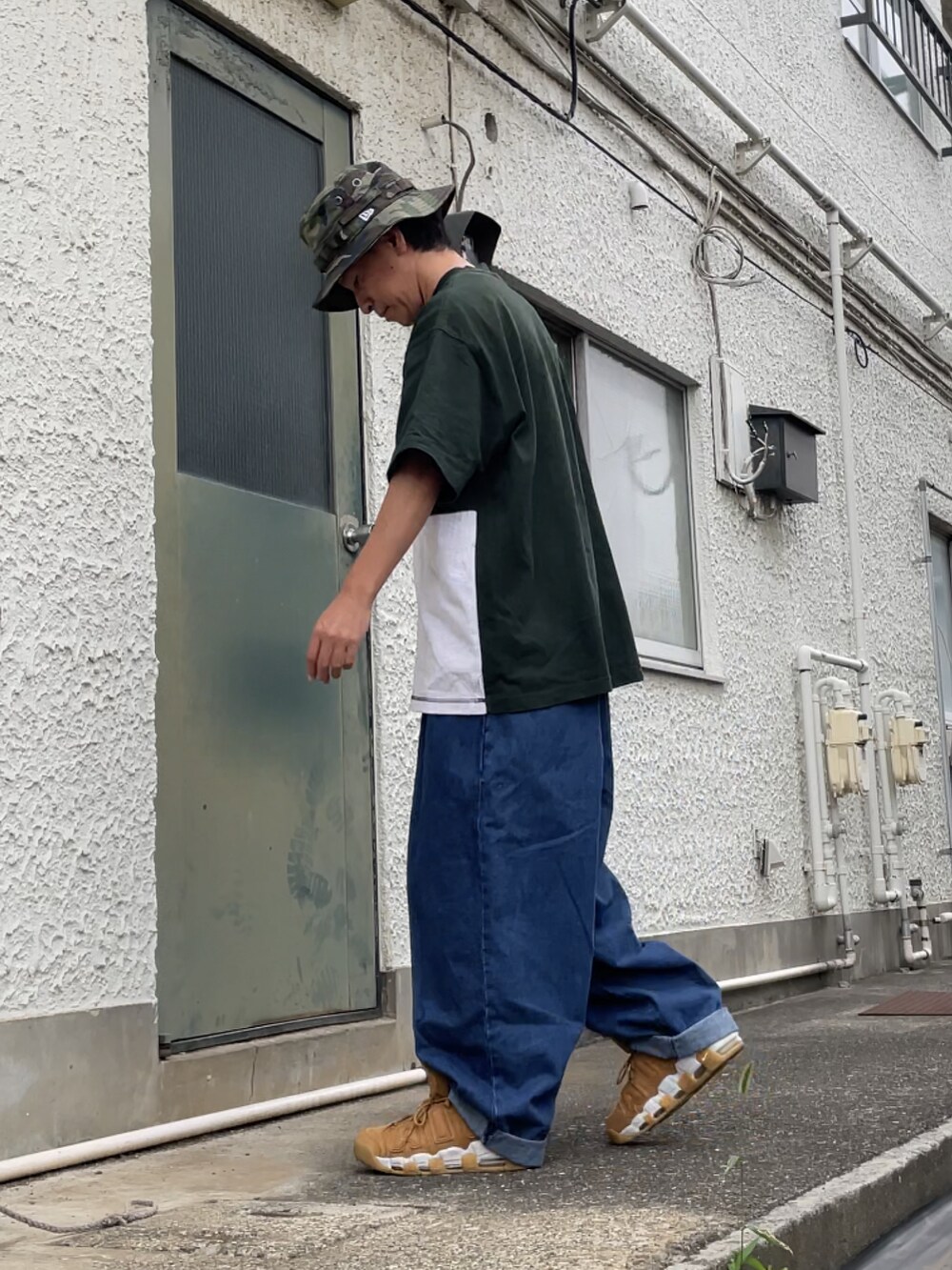 ブラウン系のスニーカー、ブルー系のデニムパンツ、グリーン系のTシャツ/カットソーを着用したメンズの秋コーディネートの2枚目の写真