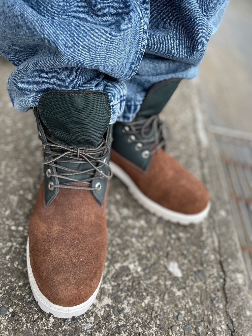 ブラウン系のブーツ、ブルー系のデニムパンツ、グリーン系のポロシャツを着用したメンズの春コーディネートの3枚目の写真