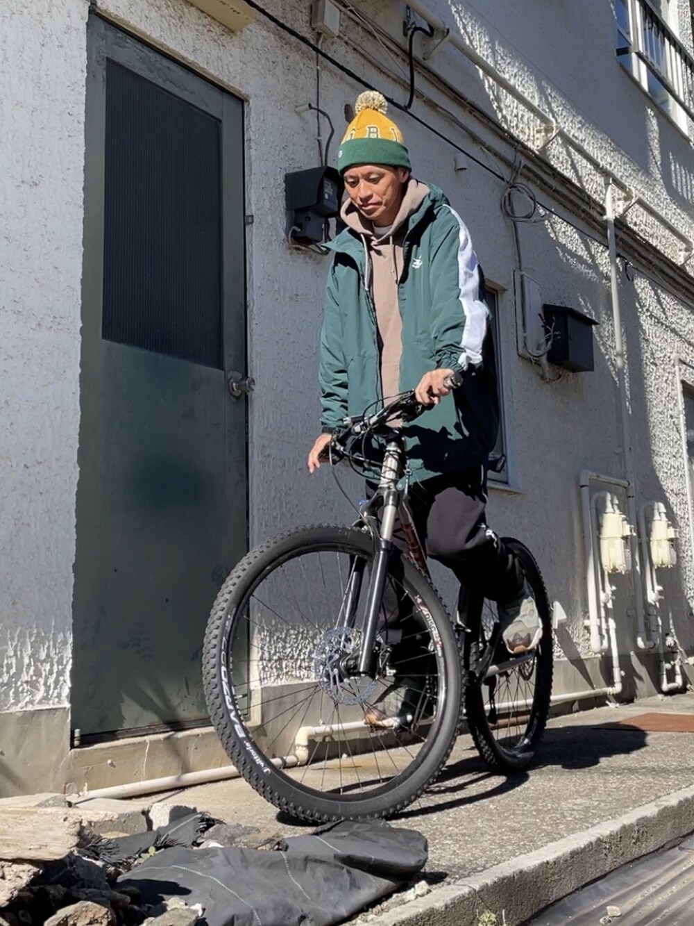 グリーン系のスニーカー、ブラック系のスウェットパンツ、グリーン系のマウンテンパーカーを着用したメンズの秋コーディネートの2枚目の写真